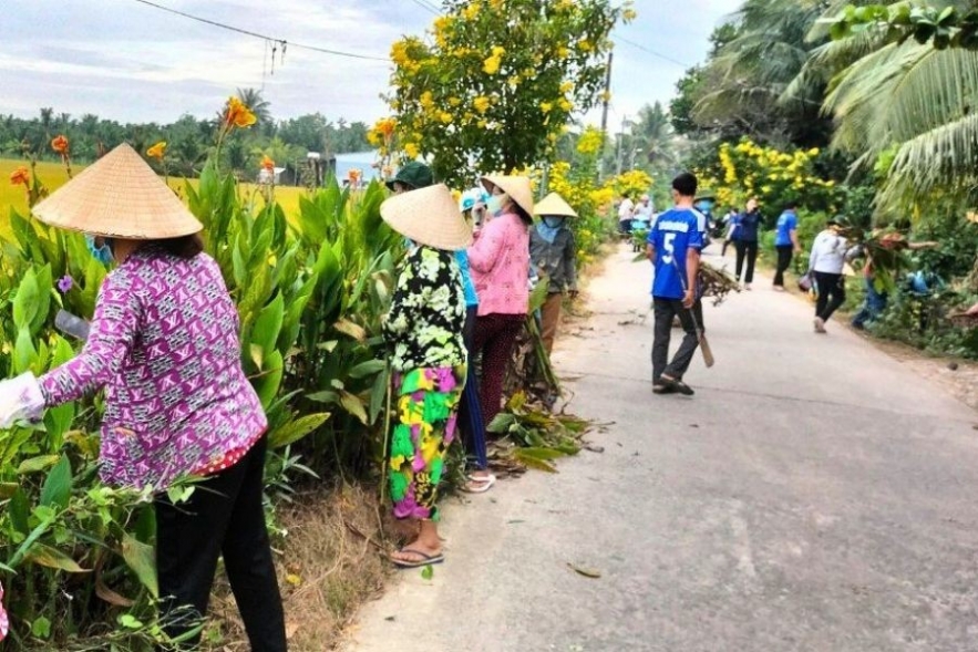 Người dân vệ sinh cảnh quan môi trường và trồng hoa trên tuyến đường hoa liên ấp Ô Ét – Bà Ép – Sóc Tre, huyện Tiểu Cần, tỉnh Trà Vinh.